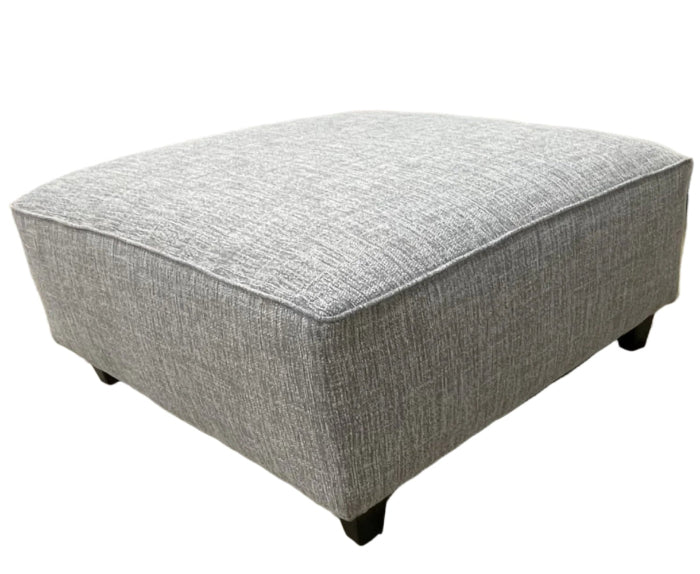 A large square cocktail ottoman in a textural solid fabric upholstery in shades of grays and whites.