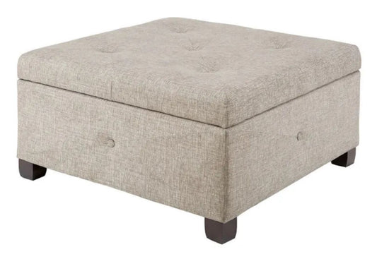 A square-shaped, beige button-tufted storage ottoman with dark brown wooden legs.